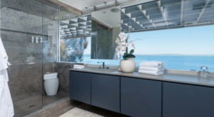 Glass encased shower, grey cabinetry with large view of the Malibu coastline.