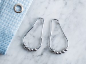 Flat lay of two chrome curtain rings and shower curtain.