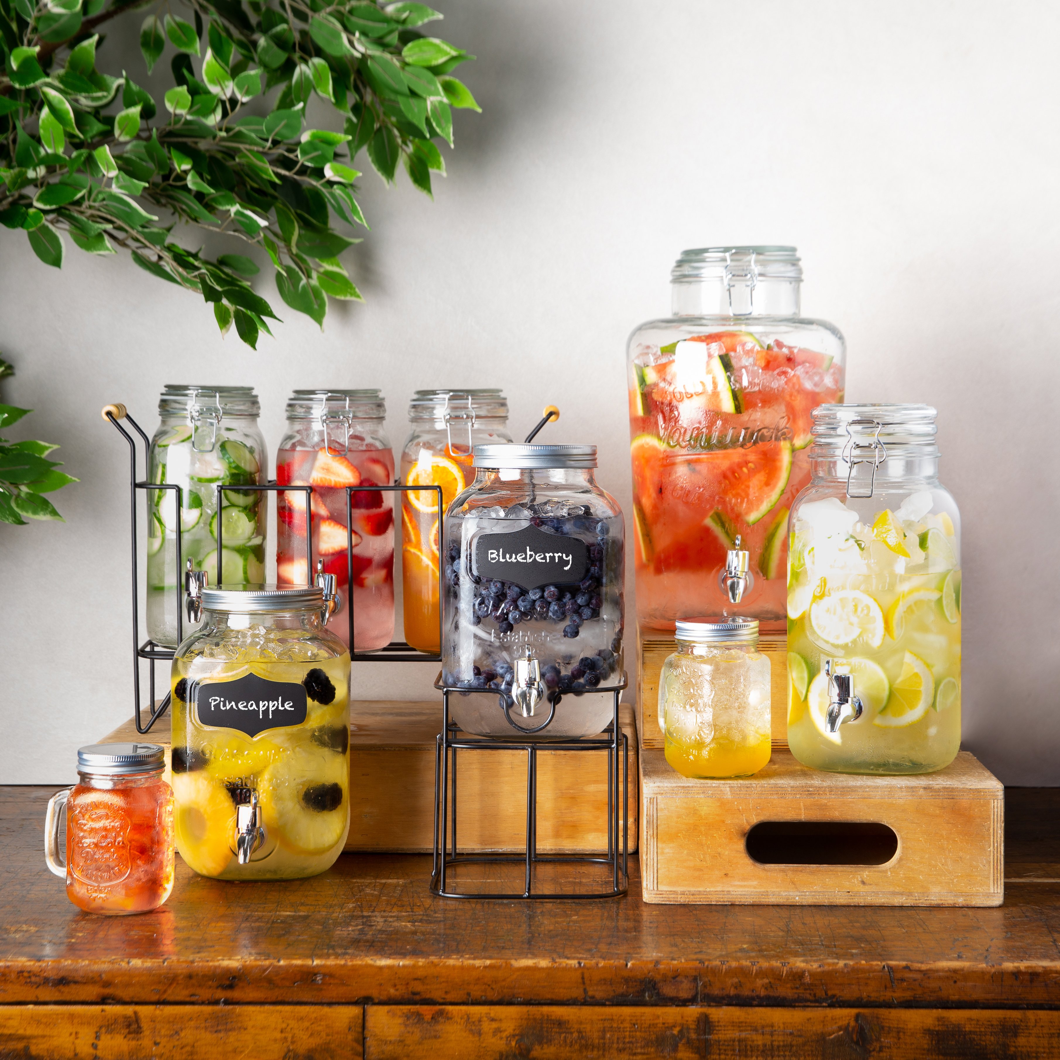 several glass beverage dispensers of different styles filled with water and various fruit