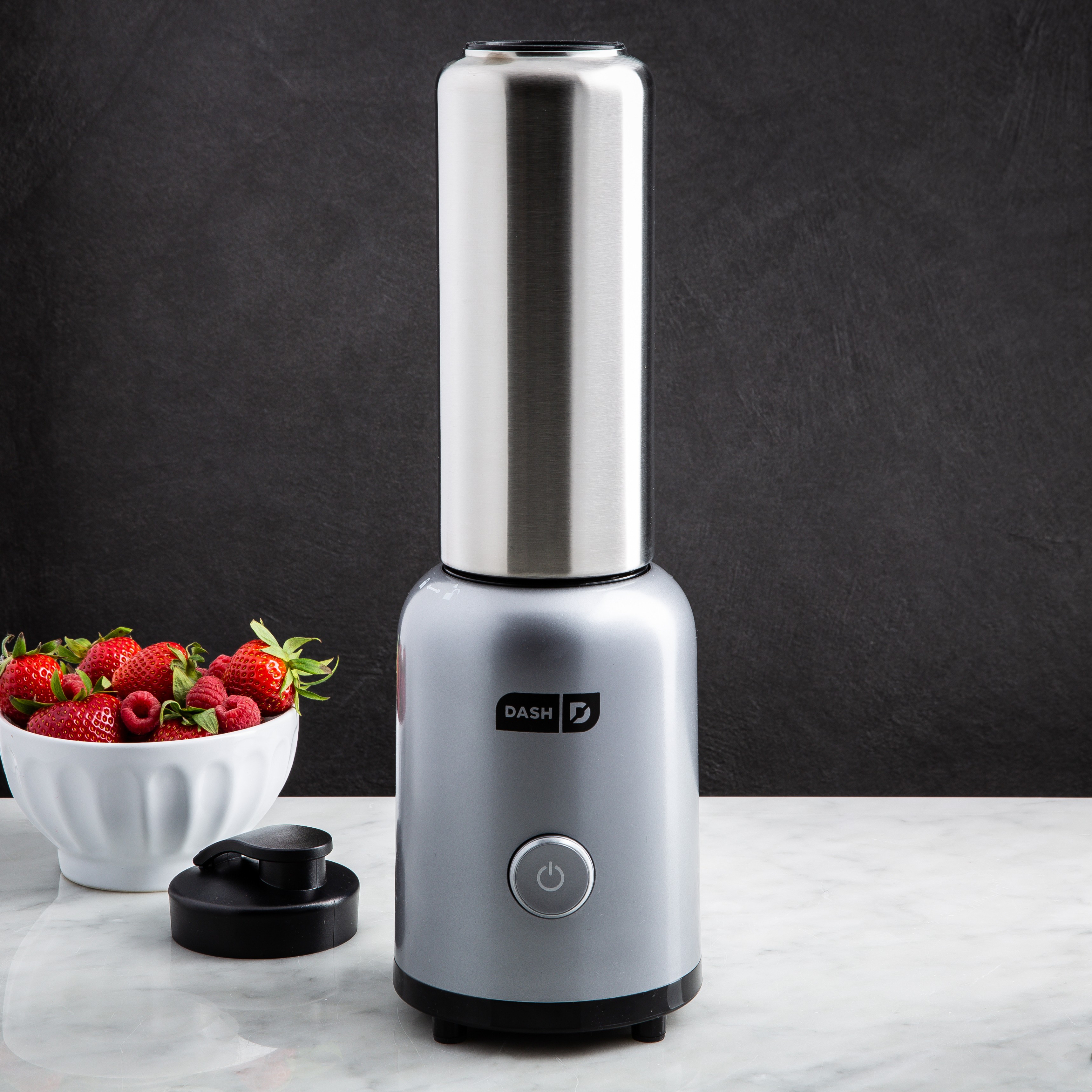 silver and stainless steel personal blender with a bowl of strawberries in the background