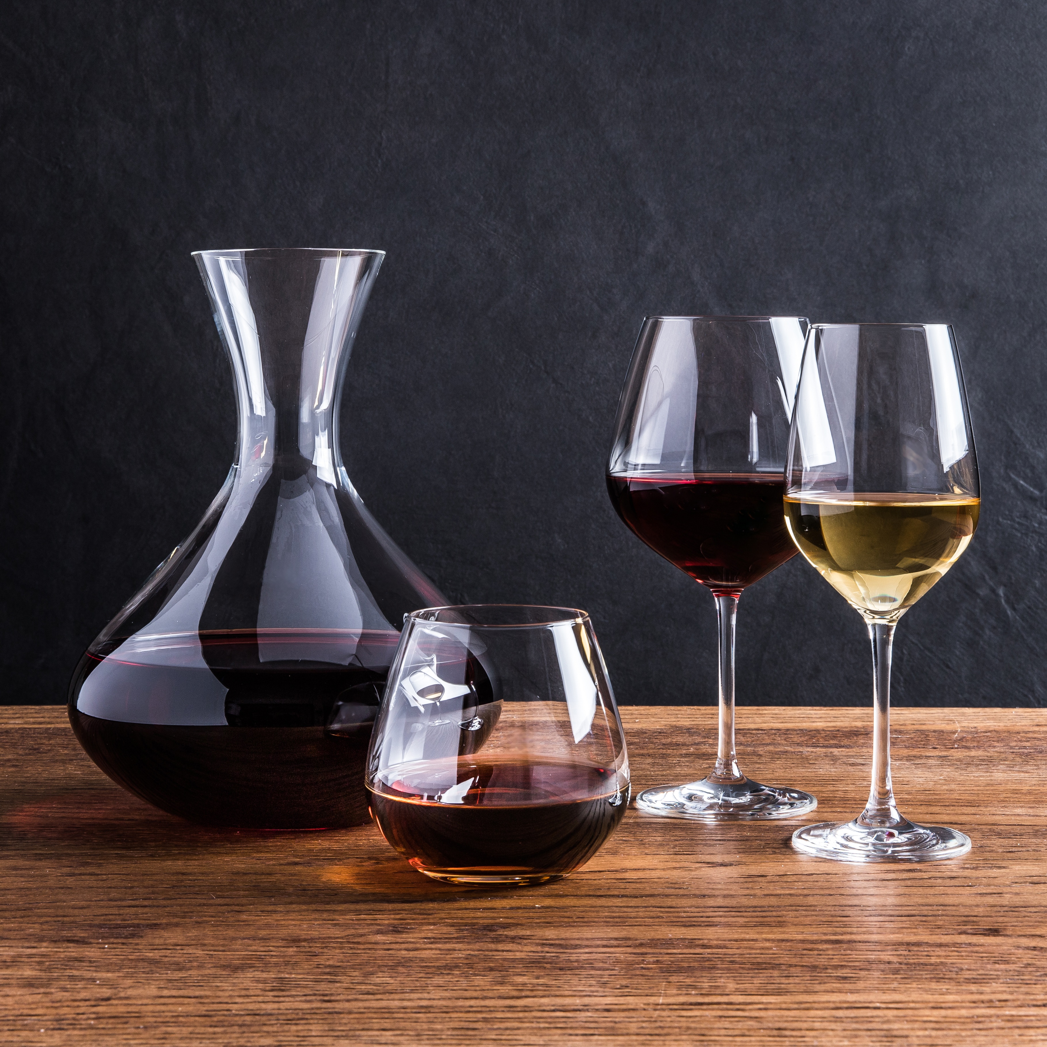 a wine decanter, stemless wine glass, red wine glass, and white wine glass filled with wine